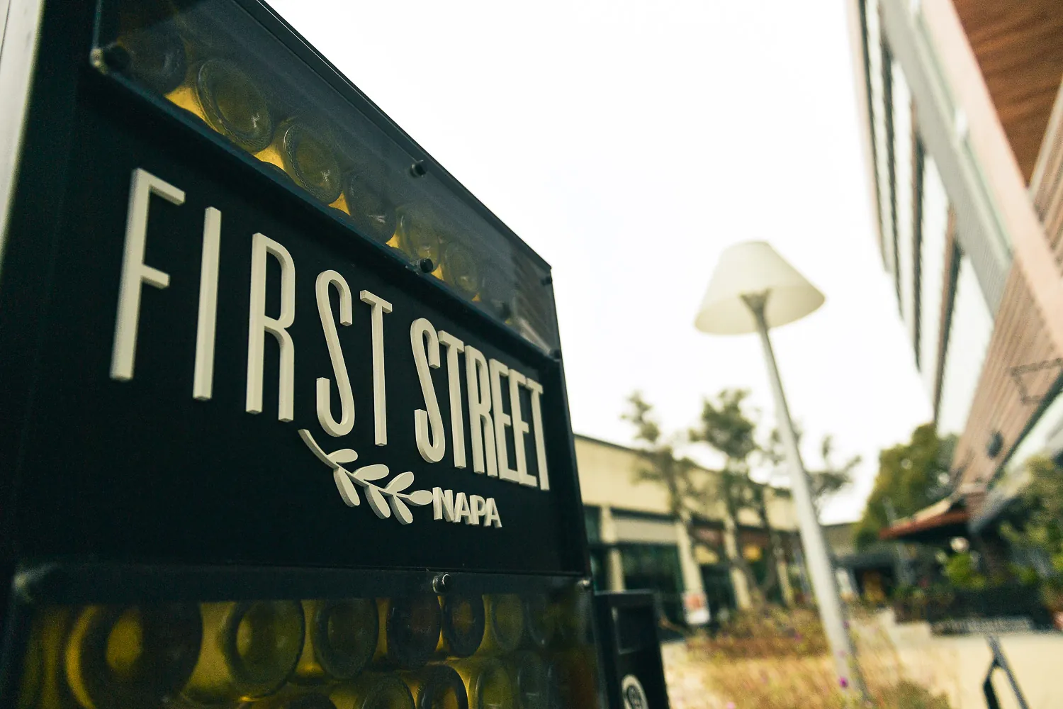 The First Street Napa sign seen from below, its frame packed with wine bottles.