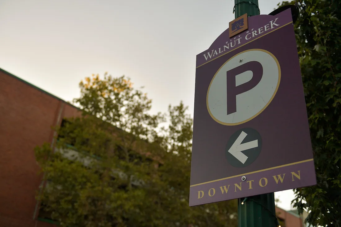 A City of Walnut Creek wayfinding sign against a dusk sky: a large parking symbol above a left-pointing arrow, with the word Downtown along the bottom.